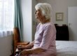 A solemn elderly woman sitting on her bed dealing with depression