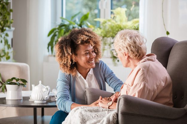 how-independent-living-in-frisco-tx-can-provide-your-desired-lifestyle Female home caregiver talking with senior woman, sitting in living room and listening to her carefully.