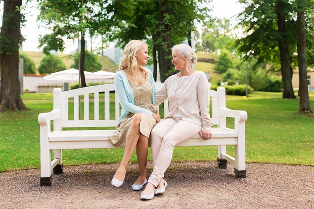 daughter with senior mother hugging on park bench daughter with senior mother hugging on park bench