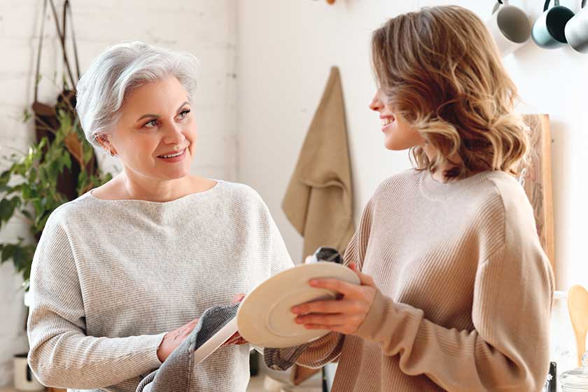 Cheerful young woman hugging aged mother sitting