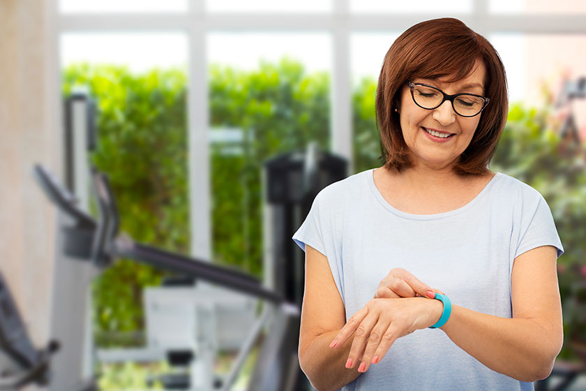 Smiling senior woman with fitness tracker in gym