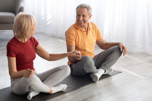 Athletic senior couple meditating together at home Athletic senior couple meditating together at home
