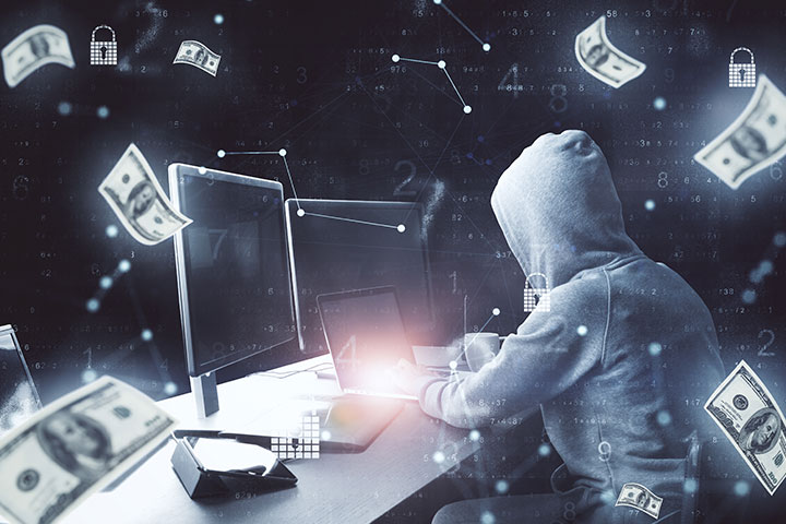 Hacker using computer and falling money bills Hacker using computer and falling money bills