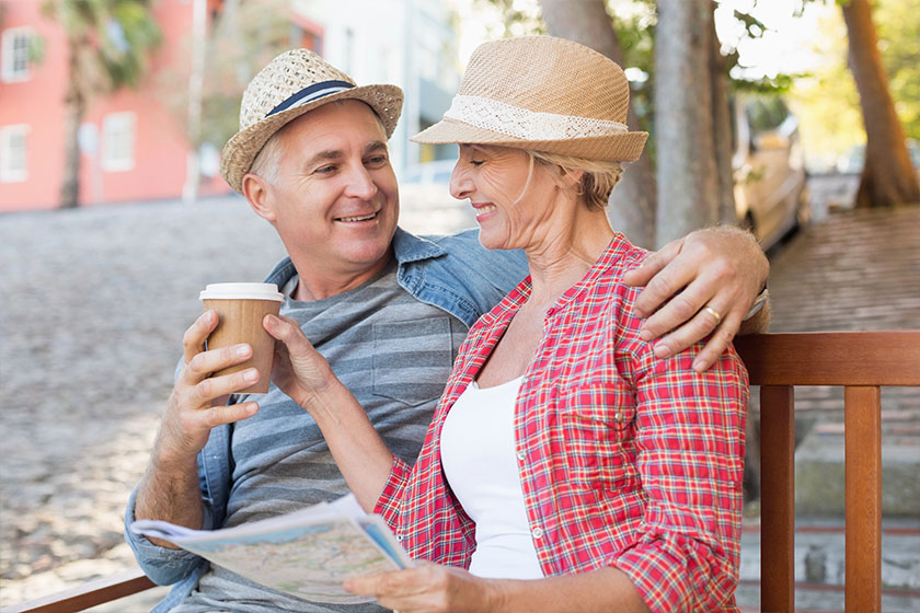 Happy tourist couple drinking coffee on a bench in the city Happy tourist couple drinking coffee on a bench in the city