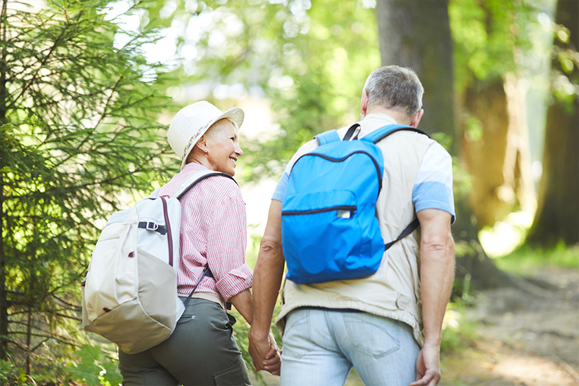 Rear view of mature couple of hikers with backpacks Rear view of mature couple of hikers with backpacks
