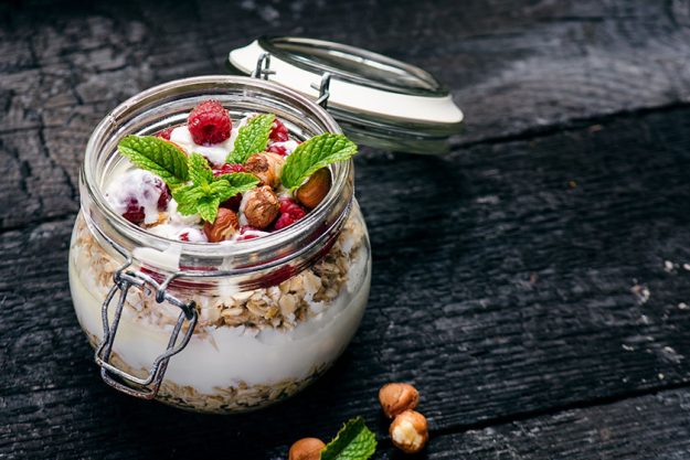 Full jar of muesli, yogurt, raspberries, nuts on a black, burnt wood table. Homemade breakfast cereals food. Healthy eating Full jar of muesli, yogurt, raspberries, nuts on a black, burnt wood table. Homemade breakfast cereals food. Healthy eating
