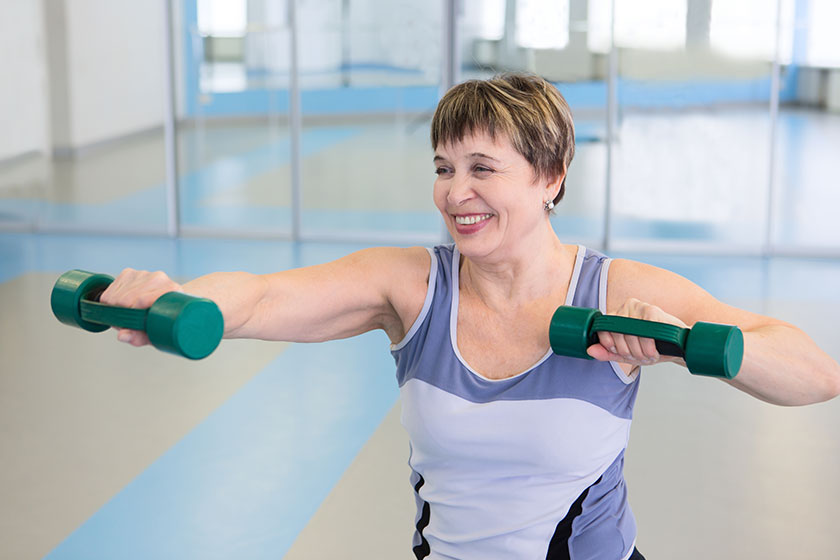 Portrait of pretty senior woman exercising with dumbbells