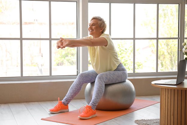 Sporty mature woman training on fitball at home Sporty mature woman training on fitball at home