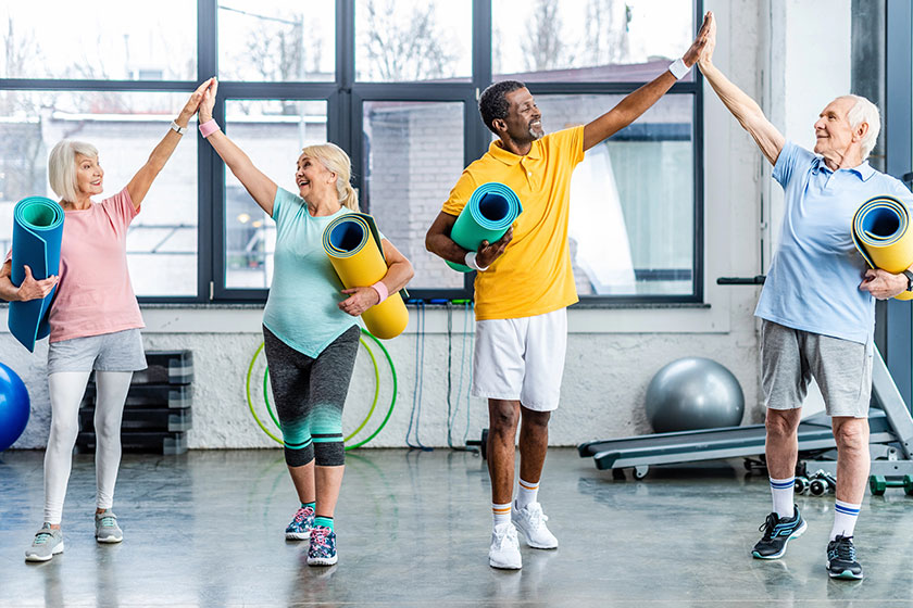 Laughing-senior-multiethnic-athletes-fitness-mats-taking-high-fives