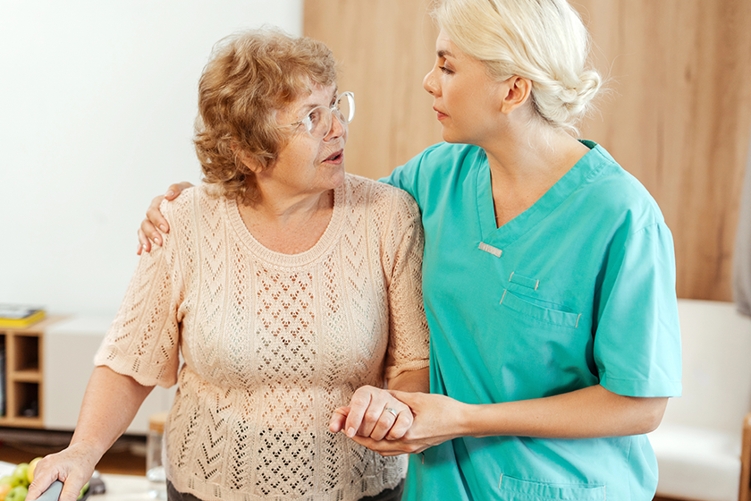 nurse-supporting-elderly-woman-using-walking-frame