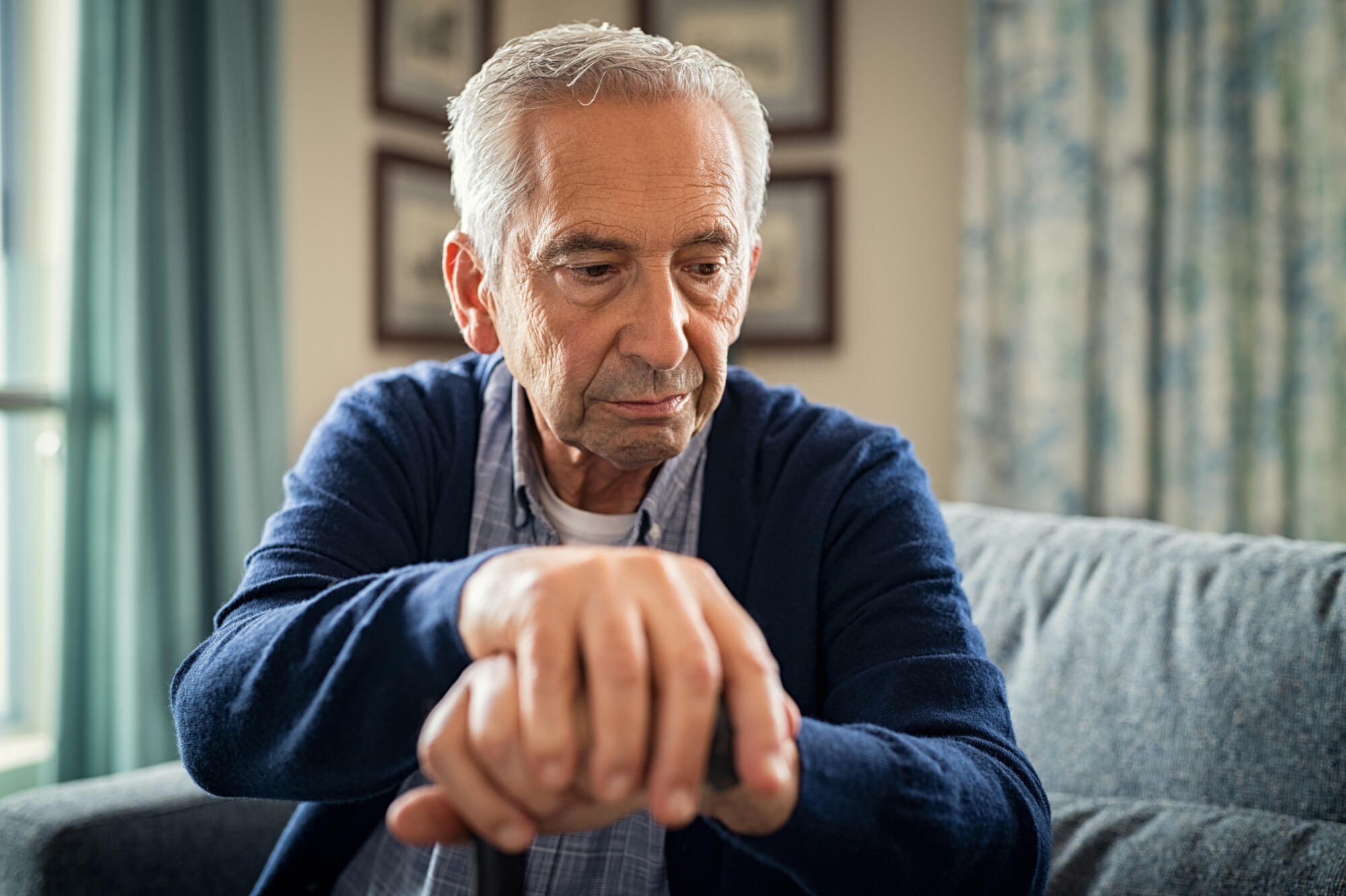 Depressed,Old,Man,Sitting,At,Home,While,Holding,Walking,Stick.