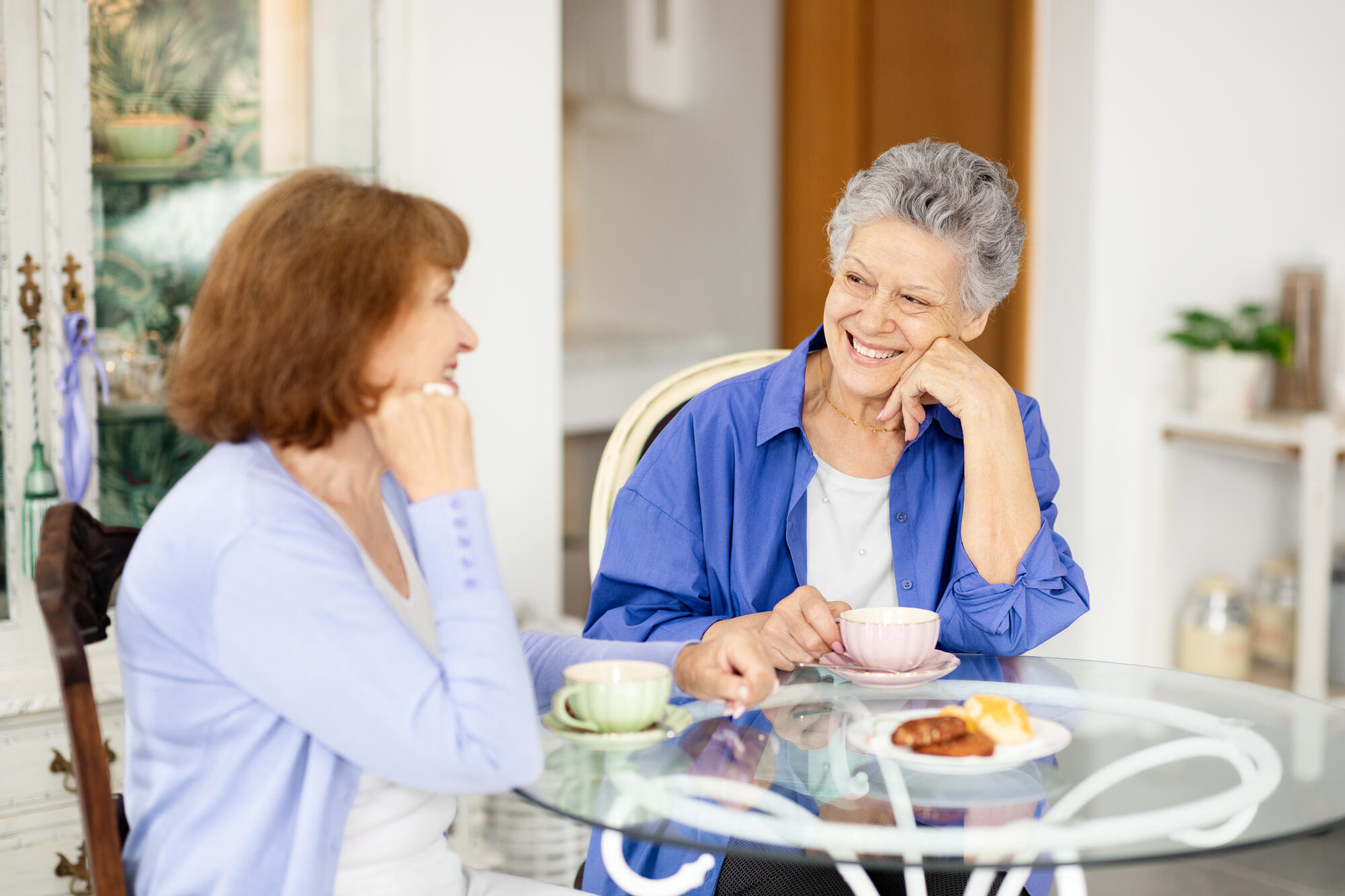 Two elderly women enjoying tea and conversation in a cozy cafe setting