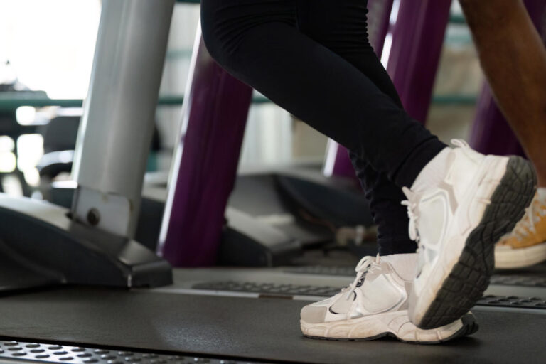 Wellness and Fitness. Close-up of feet on treadmill during workout session.